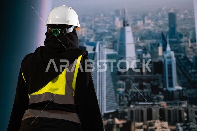 مشاريع إعمارية سعودية وطنية, صورة من الخلف لمهندسة عربية سعودية خليجية ترتدي الخوذة وسترة الحماية وتقف امام أبراج الرياض, بناء الوطن بسواعد أبنائه ومهندسيه, التطور العمراني المتميز للرياض , مهندسين المملكة العربية السعودية