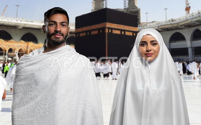 مفهوم الألفة بين الزوجين, الإكثار من العبادات في شهر رمضان المبارك, أداء مناسك الحج و العمرة, صورة مقربة لزوجان عربيان خليحيان سعوديان مبتسمان يرتديان ثياب الإحرام و ينظران الى الكاميرا، اسلاميات وعبادة, خلفية الكعبة المشرفة والحرم المكي