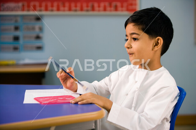 الأنشطة الترفيهيه داخل الفصل الدراسي, استخدام الأدوات الهندسية وتنمية مهارة الابتكار، طالب تمهيدي إماراتي  عربي خليجي يرتدي الزي التقليدي يتعلم الأشكال الهندسية وطريقة رسمها, تطور طرق التعليم في الإمارات