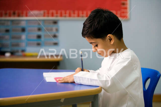 الاستمتاع بالنشاطات الترفيهيه داخل الفصل الدراسي, استخدام الأدوات الهندسية وتنمية مهارة الابتكار، صورة من الجانب لطالب تمهيدي عربي خليجي إماراتي يتعلم الأشكال الهندسية وطريقة رسمها, تطور طرق التعليم في الإمارات