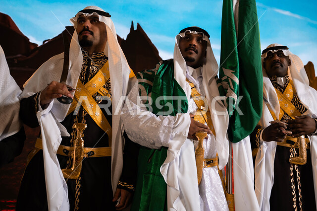 مناسبات وطنية تقليدية، فرقة العرضة الحجازية تنظر إلى شيء ما، الفلكلور الشعبي السعودي، ارتداء الدقلة والفرميلة التراثية، يوم العلم السعودي 11 مارس، الاحتفال بذكرى اليوم الوطني في 8 ربيع الأول، تعزيز الهوية الوطنية للملكة، خلفية قصر سلوى في الدرعية