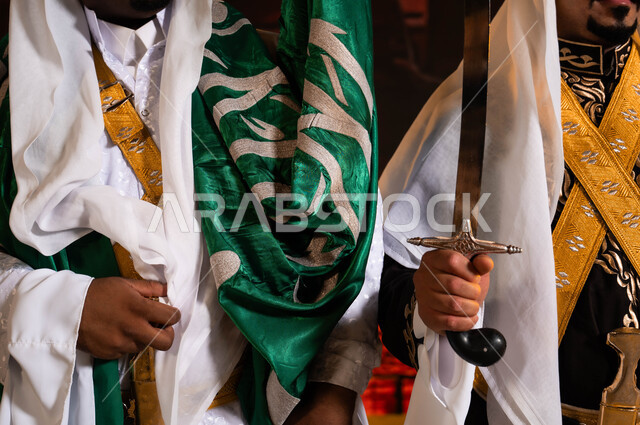 أزياء الاحتفالات والمناسبات الوطنية التقليدية، ذكرى اليوم الوطني السعودي، فنون وعروض الفلكلور التراثي السعودي، ارتداء الدقلة والفرميلة الشعبية، الاحتفال بيوم العلم السعودي 11 مارس، صورة مقربة لفرقة العرضة الحجازية والأهازيج والرقص الشعبي بالسيوف
