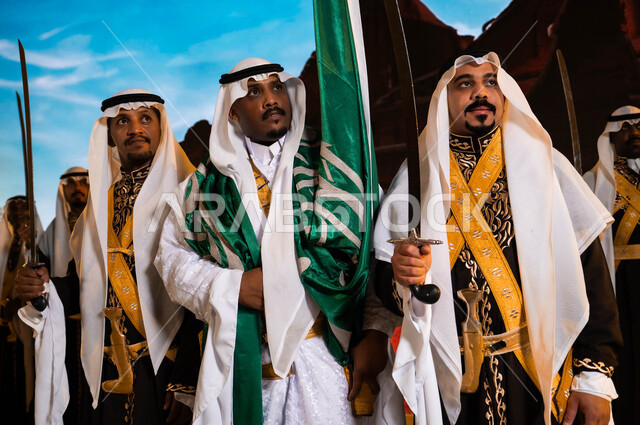 مناسبات وطنيه تقليدية 23 مارس، خلفية قصر سلوى في الدرعية في الرياض، الفلكلور الشعبي السعودي، ارتداء الدقلة والفرميلة التراثية، يوم العلم السعودي 11 مارس، الاحتفال بذكرى اليوم الوطني السعودي، فرقة العرضة الحجازية والأهازيج والرقص الشعبي تنظر إلى شيء ما