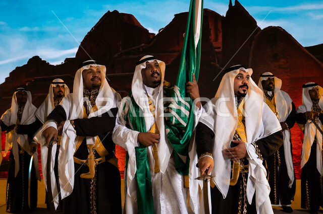 خلفية قصر سلوى في الدرعية في الرياض، الفلكلور الشعبي السعودي، احتفالات ومناسبات وطنية تقليدية، ارتداء الدقلة والفرميلة التراثية، يوم العلم السعودي 11 مارس، الاحتفال بذكرى اليوم الوطني 8 ربيع الأول، صورة مقربة لفرقة العرضة الحجازية والأهازيج والرقص الشعبي