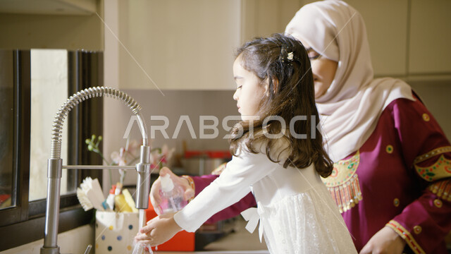 قضاء أوقات ممتعه مع الأبناء في المطبخ، الإستمتاع بأداء الأعمال المنزليه برفقة الابنه، المساعده في تنظيف وغسيل الأطباق، تربيه الأطفال على حب التعاون، صورة مقربة لأم عربية خليجية اماراتية تقف في المطبخ، غسل اليدين بالماء والصابون والمحافظة على النظافه الشخص
