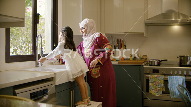 المساعده في تنظيف وغسيل الأطباق، تربيه الأطفال على حب التعاون، الإستمتاع بأداء الأعمال المنزليه برفقة الأبناء، أم عربية خليجية اماراتية تقف مع ابنتها في المطبخ، انجاز المهام الروتينيه في المنزل، غسل اليدين بالماء والصابون والمحافظة على النظافه الشخصية.