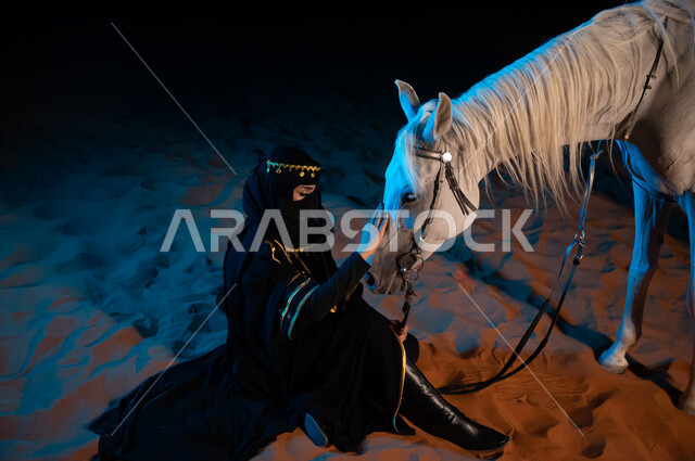Sitting on the golden sands, inheriting the love of horses from the ancestors and spreading it among the people of the country, wearing the costumes of the Saudi founding day 1727, the background of the desert nature, entertainment activities and events,