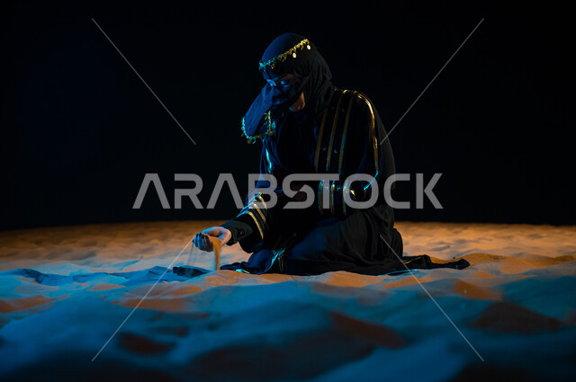 الجلوس على الرمال الذهبية الناعمة، الاعتزاز والفخر الدائم بالهوية الوطنية السعودية, مشاعر الحب والانتماء للملكة, مفهوم حب الوطن والانتماء إليه, امرأة عربيه خليجية ترتدي عباءة سوداء و تمسك تراب الوطن افتخارا بأصولها و جذورها، التعبيرعن الحب والولاء للبلاد