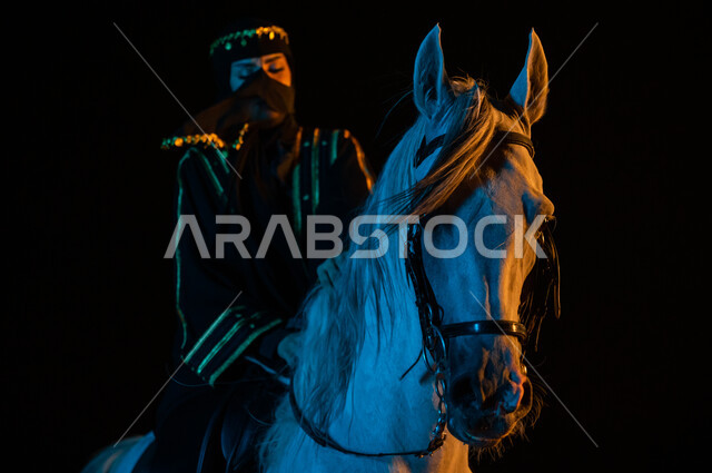 ممارسة هواية ركوب الخيل، حب الفروسيه وركوب الجواد , ملاطفة الخيول والاعتناء بهم، صورة مقربة لإمرأة عربيه خليجية ترتدي العباءة السعودية والبرقع تمتطي فرسها الأبيض في وقت الليل، ارتداء أزياء يوم التأسيس السعودي1727 ،ذكرى يوم التاسيس السعودي 22 فبراير