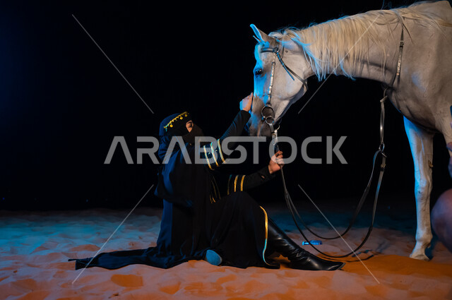 حب الفروسيه وركوب الخيل، توارث حب الجياد من الاجداد ونشره بين أبناء الوطن, ارتداء أزياء يوم التأسيس السعودي1727 ، خلفية الطبيعة الصحراوية، الجلوس على الرمال الذهبية، إمرأة عربيه سعودية محجبه تقوم بمداعبه فرسها في الصحراء، ذكرى يوم التاسيس السعودي 22 فبراير