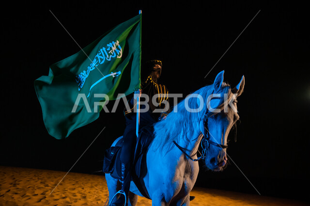 Commemoration of Saudi Flag Day, March 11, celebration with horses on National Day, September 23, founding of the first Saudi state 1727 AD, founding day, February 22, close-up photo of a Saudi Arab woman wearing an abaya and burqa, carrying the flag of the Kingdom and riding an Arabian horse, desert nature background