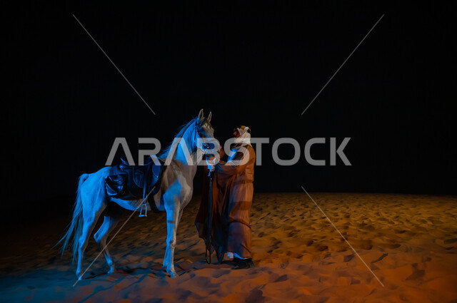 مشاركة الجياد في المناسبات والأعياد الوطنية، حب الفروسيه وركوب الخيل, ارتداء أزياء اهل المنظقه الوسطى ,رجل عربي سعودي يرتدي البشت والغترة يقف بجانب فرسه في الصحراء, ذكرى يوم التأسبس المملكة 22 فبراير، يوم التأسيس السعودي 1727 م ،صورة الجسم بالطول الكامل