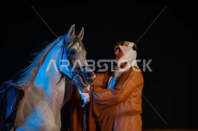 مشاركة الجياد في المناسبات والأعياد الوطنية، حب الفروسيه وركوب الخيل, أزياء اهل المنظقه الوسطى , صورة مقربة لرجل عربي سعودي زي يوم التأسيس 1727 م التقليدي الشعبي يقوم بملاطفة فرسه والنظر اليه, ذكرى يوم تأسيس المملكة 22 فبراير