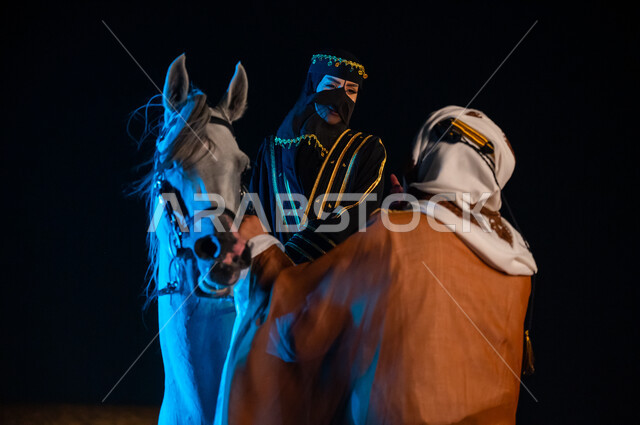 حب الفروسيه وركوب الأحصنة, ممارسة هواية ركوب الخيل, دردشة وحوارات وديه، ذكرى يوم التاسيس السعودي 22 فبراير، صورة مقربة لإمرأة ورجل عربيان خليجيان سعوديان يرتديان ازياء يوم التأسيس السعودي1727 م و يتبادلان الاحاديث الجانبيه المسليه في الخارج ليلا