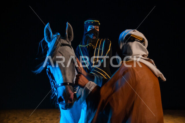 The background of desert nature and golden sands, chat and friendly dialogues, the anniversary of the Saudi founding day February 22, a close-up of a Saudi Gulf woman and man dressed in the costumes of the Saudi founding day 1727 AD and exchanging enterta