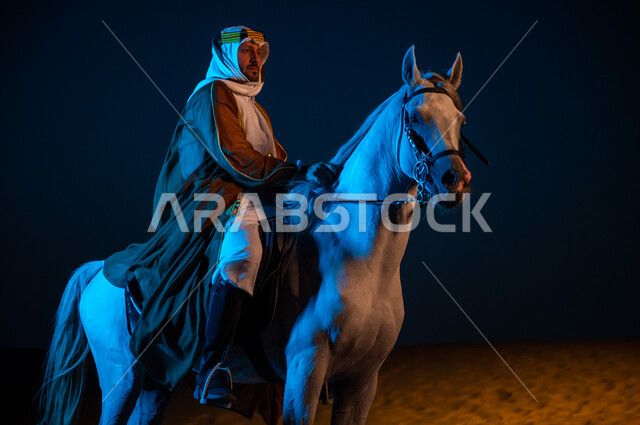 تربيه المواشي و الحيوانات الأليفه، مشاركة الجياد في المناسبات والأعياد الوطنية, ارتداء أزياء اهل المنطقه الوسطى , رجل عربي سعودي يرتدي زي  التأسيس 1727 م التقليدي الشعبي يقوم بامتطاء فرسه ومداعبته ليلا في الصحراء, ذكرى يوم تأسيس المملكة 22 فبراير