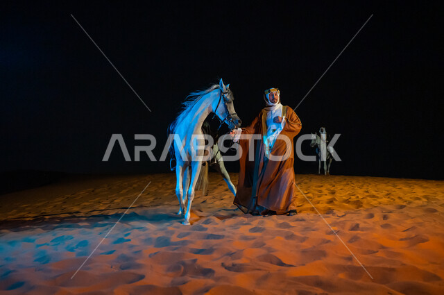 تجول الفرسان في الطبيعه الرملية الذهبية الناعمة، مشاركة الجياد في المناسبات والأعياد الوطنية، ارتداء أزياء اهل المنطقه الوسطى , رجل سعودي يرتدي زي يوم التأسيس 1727 م يقف بجانب فرسه في الصحراء, ذكرى تأسيس المملكة 22 فبراير، صورة الجسم بالطول الكامل