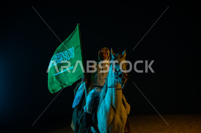 يوم العلم 11 مارس , ذكرى تأسيس المملكة 22 فبراير، ممارسة هواية تربيه الخيول، الاحتفال باليوم الوطني السعودي 23 سبتمبر، رجل عربي خليجي سعودي يرتدي زي يوم التأسيس 1727 م يمتطي الخيل العربي ويحمل بيده علم المملكة السعودية, الشغف بتربية الجياد الأصيلة