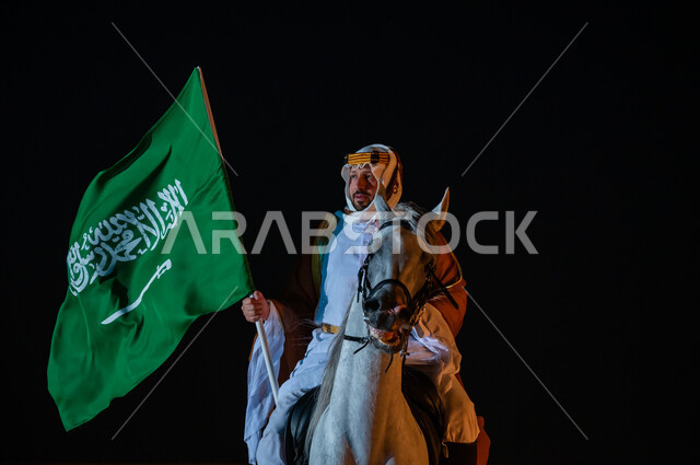 الشغف بتربية الجياد الأصيلة, ذكرى تأسيس المملكة 22 فبراير، يوم العلم 11 مارس , ممارسة هواية تربيه الخيول، الاحتفال باليوم الوطني السعودي 23 سبتمبر، رجل عربي خليجي سعودي يرتدي زي يوم التأسيس 1727 م يمتطي الخيل العربي ويحمل بيده علم المملكة السعودية