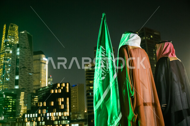 التعبير عن الحب والولاء في يوم العلم 11 مارس, الاحتفال بذكرى اليوم الوطني 23 سبتمبر , أزياء المناسبات والاحتفالات الشعبية, صورة من الخلف لرجلين عربيين سعوديبن خليجيين يرتديان الزي السعودي التقليدي، الوقوف باعتزاز بالوطن، المركز المالي (كافد).