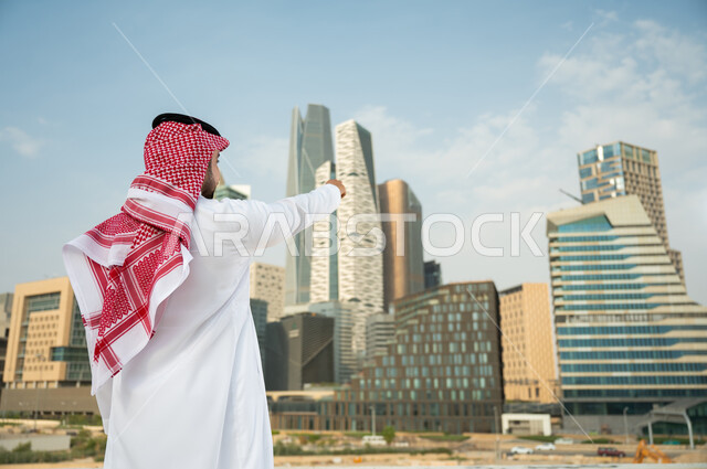 The distinguished architectural engineering art in Riyadh, the reference to the skyscrapers in Riyadh, a back image of a Saudi Arabian Gulf man wearing the traditional shemagh and thobe and pointing with his hand to the financial towers in Kafed, the grow