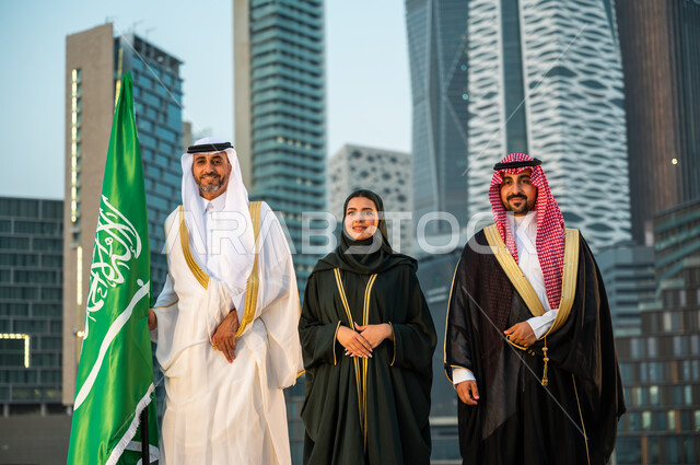 النظر إلى الكاميرا بإيماءات الثقة والفخر, ارتداء الأزياء الشعبية التقليدية, الاحتفال بالمناسبات الوطنية السعودية, مواطنون عرب سعوديون خليجيون يحتفلون باليوم الوطني 23 سبتمبر, الوقوف بثقة في يوم العلم 11 مارس, خلفية الأبراج الاقتصادية في الرياض