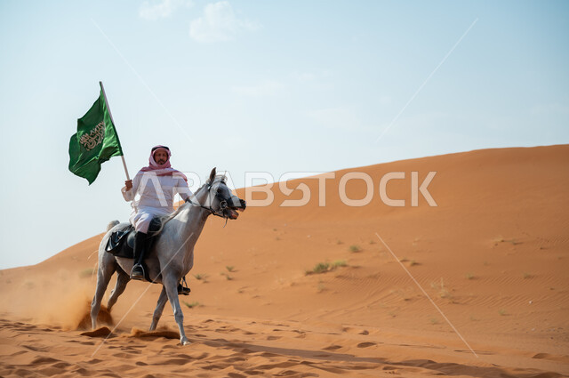 علاقة أبناء الوطن بالخيل السعودي، فارس عربي خليجي سعودي يمتطي فرس عربي أصيل ويرفع علم السعودية، ذكرى اليوم الوطني لتوحيد المملكة 23 سبتمبر، يوم العلم السعودي 11 مارس، تعزيز مفهوم الوحدة الوطنية، ممارسة هواية ركوب الأحصنة في الطبيعة الصحراوية