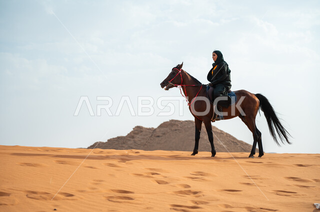 شغف الفروسية وممارسة هواية ركوب الخيل، سيدة عربية خليجية سعودية محجبة ترتدي العباية وتتجول في الصحراء السعودية على ظهر جواد عربي أصيل، توارث حب الخيول من الأجداد ونشره بين أبناء الوطن، إمتطاء الحصان السعودي على الرمال الناعمة في المناطق الصحراوية