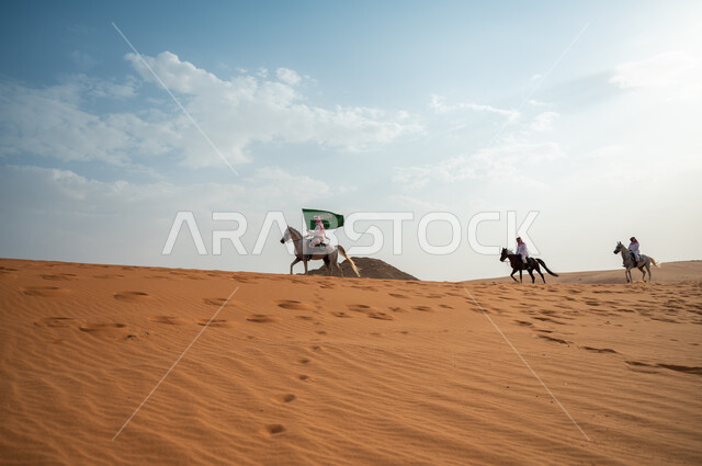 Knights riding horses in the desert, commemorating National Day, participating in horse riding events on National Day 8 Rabi’ al-Awwal, celebrating Saudi Flag Day March 11, a group of Saudi Gulf Arab men racing on horseback and raising the Kingdom’s flag, the strength and speed of the Saudi horse.