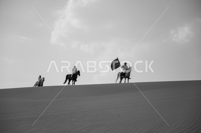 إحياء ذكرى اليوم الوطني، هواية امتطاء الجياد في الصحراء، العيد الوطني 8 ربيع الأول، الاحتفال بيوم العلم السعودي 11 مارس، صورة بالأبيض والأسود لفرسان عرب خليجيين سعوديين يتسابقون على ظهر الاحصنة ويرفعون علم المملكة، قوة وسرعة الخيل السعودي