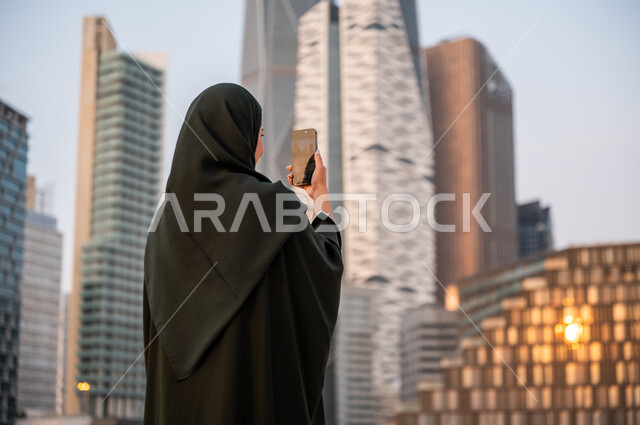 Taking souvenir photos of the towers of the King Abdullah Financial District, publishing and sharing the urban and urban development of the economic facilities and landmarks of Riyadh on social media, a picture from the back of a young Saudi Arabian Gulf 