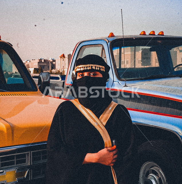 الاحتفال بتوحيد المملكة العربية السعودية 1727 م، ذكرى يوم التأسيس السعودي في 22 فبراير, صورة مقربة لإمرأة عربية خليجية سعودية محجبة ترتدي العباءة والبرقع تنظر الى الكاميرا, مؤسس الدوله السعودية الاولى الامام محمد بن سعود, خلفية سيارات شيفروليه