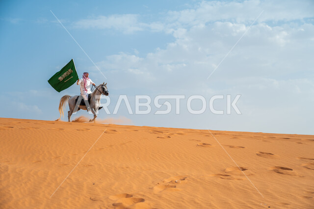 مشاعر الإنتماء وحب البلاد, هواية ركوب الخيل وشغف الفروسية، فارس عربي خليجي سعودي يركب فرس عربي أصيل يرفع علم السعودية في الصحراء، ذكرى اليوم الوطني لتوحيد المملكة ، العيد الوطني 23 سبتمبر، يوم العلم السعودي 11 مارس