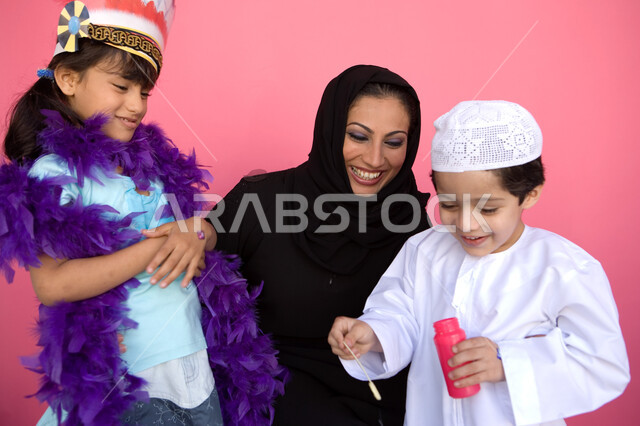 تنمية مهارات الأطفال الحركية, اللعب بالفقاعات المائية بإيماءات السعادة والفرح, قضاء الأوقات بالأنشطة الترفيهية الممتعه, بورتريه لعائلة عربية خليجية إماراتية تستمتع بصنع فقاعات الصابون, مفهوم الأسرة السعيدة, زرع روح المحبة بين الأبناء, خلفية وردية