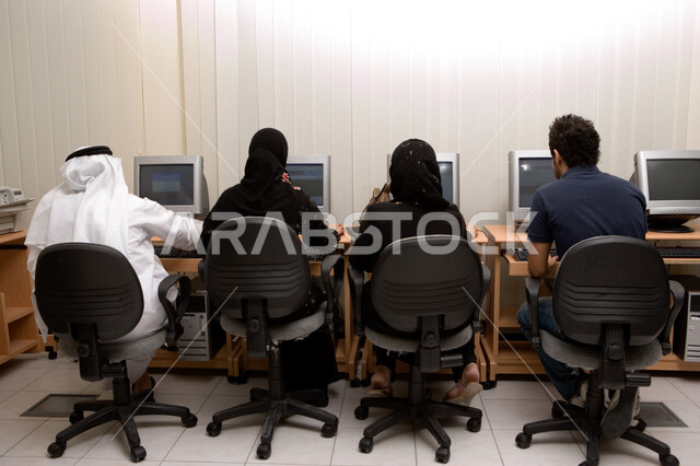 Practical application for students in computer rooms, advanced curricula and e-learning in the Emirates, teaching students how to use computer technologies in universities, a back image of Emirati Gulf Arab students sitting in a computer room and doing wo