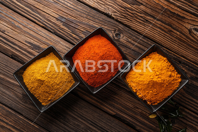 مجموعة من التوابل الناعمة في أطباق صغيرة على طاولة خشبية, منكهات وبهارات للمأكولات والأطعمة, انواع توابل متعددة ملونة