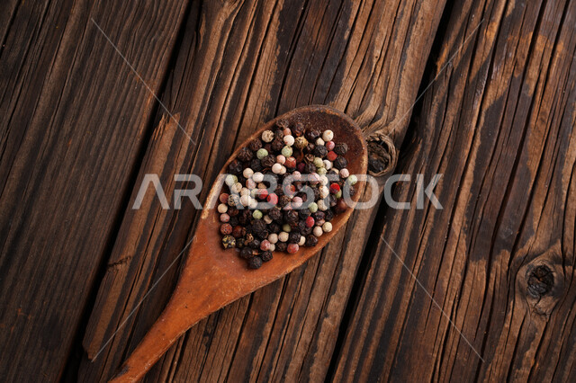 حبيبات صحيحة من التوابل في ملعقة خشبية على طاولة خشب, فلفل أسود حبة كاملة, منكهات وبهارات للمأكولات والاطعمة