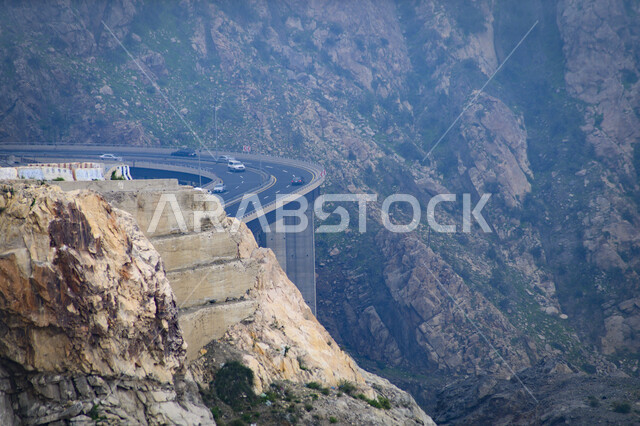 A twisted and bumpy asphalt road in the middle of the rocky Al Hada Mountains in the city of Taif, the mountainous environment, peaks and heights in the Kingdom of Saudi Arabia, natural tourist places, nature background