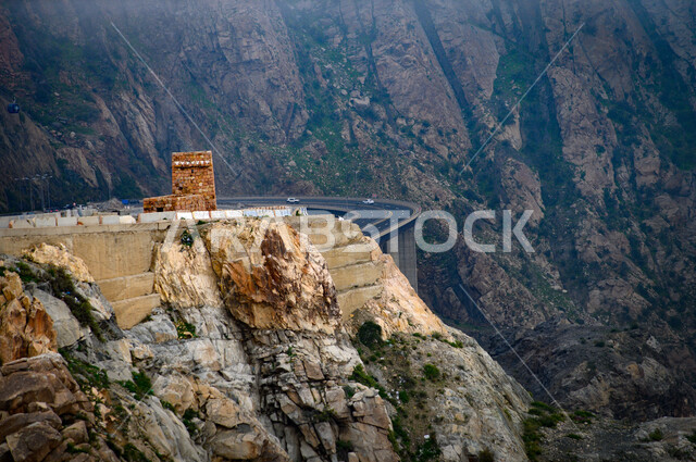 A twisted and bumpy asphalt road in the middle of the rocky Al Hada Mountains in the city of Taif, the mountainous environment, peaks and heights in the Kingdom of Saudi Arabia, natural tourist places, nature background