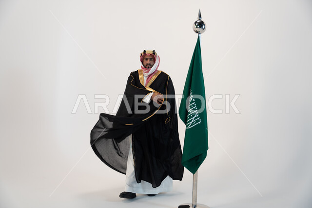 اليوم الوطني السعودي 23 سبتمبر، ذكرى يوم العلم 11 مارس، بورتريه لرجل عربي خليجي سعودي يرتدي البشت والشماغ يقف بجانب البيرق، تأسيس المملكة العربية السعودية  1727 م، مؤسس الدوله السعوديه الاولى الامام محمد بن سعود، صورة الجسم بالطول الكامل، خلفية بيضاء