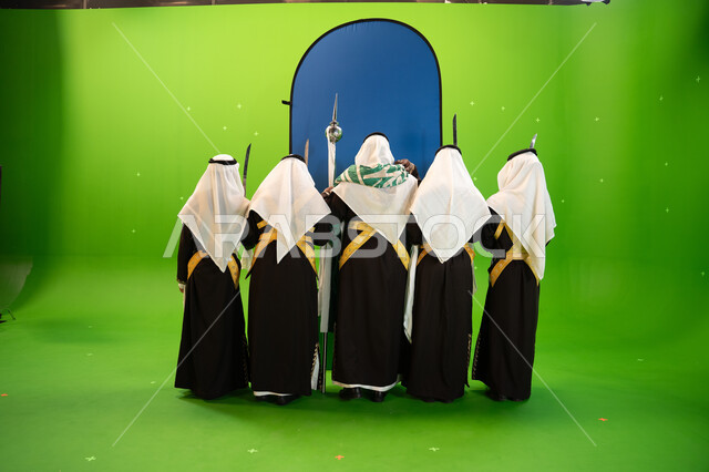  إبراز التراث السعودي العربي ،صورة من الخلف لفرقة العرضة النجدية في الاحتفالات و المناسبات الوطنية، إرتداء ازياء العرضة النجدية الشعبية، الاحتفال بذكرى اليوم الوطني السعودي 23 سبتمبر ، صورة الجسم بالطول الكامل، خلفية خضراء وزرقاء، كروما