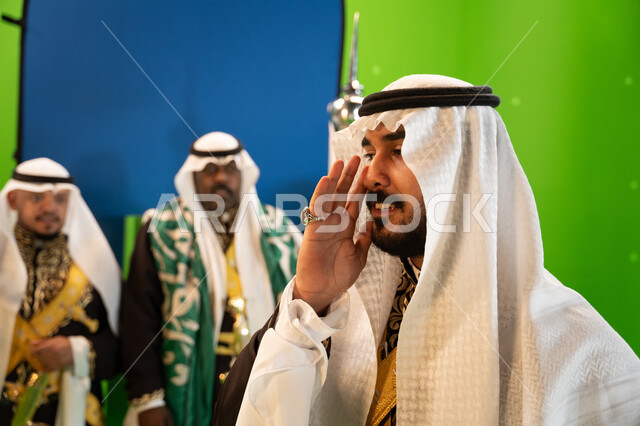 الاحتفال بذكرى اليوم الوطني السعودي 23 سبتمبر ،يوم العلم السعودي 11 مارس ،عروض و فنون الفلكلور التراثي السعودي، فرقة العرضة النجدية في المناسبات الوطنية، صورة مقربة لرجل سعودي يرتدي الغترة والدقله يقوم بأداء الغناء الشعبي ،  خلفية خضراء وزرقاء، كروما