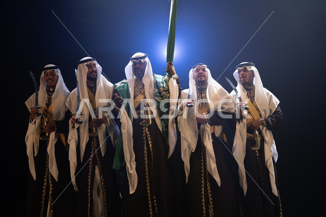 المشاركة في تنمية الوطن ورفع قدره, فرقة عروض الفلكلور التراثي في العيد الوطني في 8 ربيع الاول، الاحتفال بيوم العلم 11 مارس, ارتداء زي العرضة النجدية الشعبية، الرقص الشعبي بالسيوف والأهازيج والاحتفالات في المناسبات الوطنية، خلفية سوداء مع إضاءة بيضاء