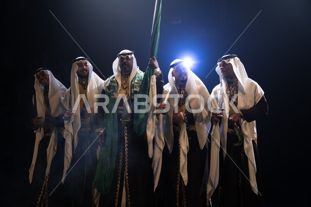 مفهوم الوحدة الوطنية, أهازيج واحتفالات في المناسبات السعودية، الرقص الشعبي بالسيوف في العرضة النجدية، ارتداء زي الدقلة والفرميلة الشعبية، فرقة عروض الفلكلور التراثي في العيد الوطني في 23 سبتمبر، الاحتفال بيوم العلم 11 مارس, خلفية سوداء مع إضاءة بيضاء