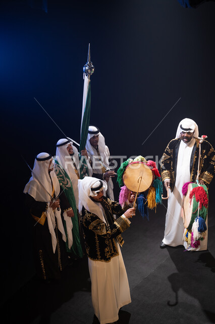 المناسبات والفعاليات الوطنية, ارتداء زي الدقلة والفرميلة الشعبية, صورة من الأعلى لفرقة عروض الفلكلور التراثي تحتفل في يوم العلم في 11 مارس, استذكار اليوم الوطني في 23 سبتمبر, الرقص الشعبي والأهازيج والاحتفالات للعرضة النجدية, خلفية سوداء