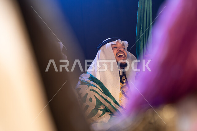 ذكرى يوم العلم السعودي في 11 مارس, مشاركة فرق الفلكلور التراثي في الاحتفالات والمناسبات الوطنية, صورة مقربة من الجانب لرجل عربي خليجي سعودي يحتفل باليوم الوطني في 23 سبتمبر, إظهار حب الوطن والانتماء إليه, ارتداء الأزياء الشعبية التقليدية, خلفية سوداء