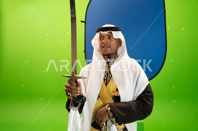 العيد الوطني السعودي 23 سبتمبر، الاحتفال بذكرى اليوم الوطني السعودي بإيماءات السعادة ، الرقصات والفعاليات الشعبية و الأهازيج في العرضة النجدية في المناسبات الوطنية، صورة مقربة لرجل عربي سعودي يرتدي الغترة والدقلة يرقص بالسيف، خلفية خضراء وزرقاء ،كروما