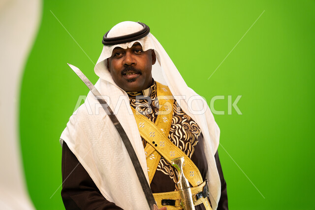 الرقص والفعاليات الشعبية و الأهازيج في العرضة النجدية في المناسبات الوطنية، الاحتفال بذكرى اليوم الوطني السعودي ،العيد الوطني السعودي 23 سبتمبر، صورة مقربة لرجل عربي خليجي سعودي يرتدي الغترة والدقلة يرقص بالسيف، خلفية خضراء ،كروما