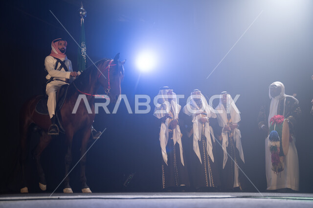 Horse riding activities and events during Saudi holidays, participation of horses in national celebrations, a Saudi Arabian Gulf horseman riding a horse and holding the Kingdom’s flag with pride and respect, traditional folklore band performances on Natio