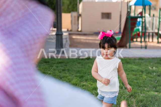 فتاه جميلة مصابة بملازمة داون تقضي وقتها في نزهه مع والدها بالمنتزه ، اب سعودي خليجي يلعب مع ابنته في الهواء الطلق ، أصحاب الهمم ، ذوي الاحتياجات الخاصة